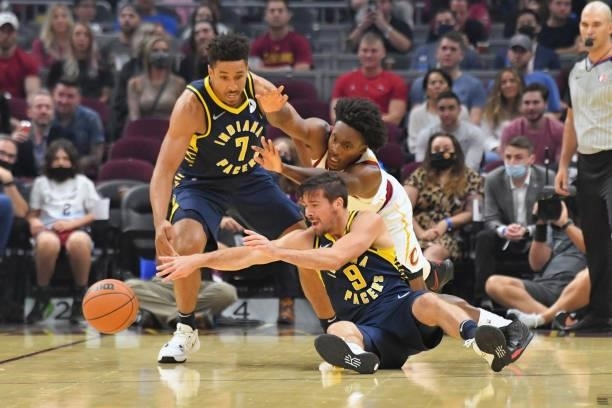 Malcolm Brogdon and Brad Wanamaker of the Indiana Pacers fight Collin Sexton of the Cleveland Cavaliers for a loose ball during the first quarter at...