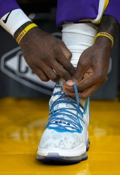 Detailed view of LeBron James of the Los Angeles Lakers as he ties the laces of the basketball sneakers worn against the Golden State Warriors at...