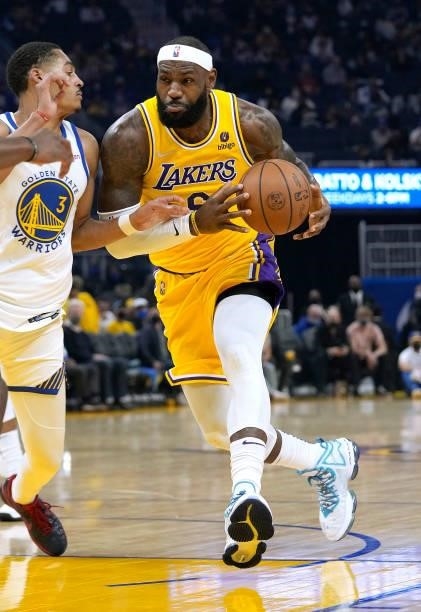 LeBron James of the Los Angeles Lakers drives towards the basket on Jordan Poole of the Golden State Warriors at Chase Center on October 08, 2021 in...
