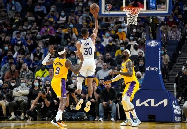 Stephen Curry of the Golden State Warriors shoots a three-point shot over LeBron James and Kent Bazemore of the Los Angeles Lakers at Chase Center on...