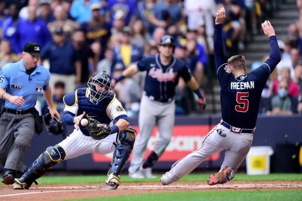 Freddie Freeman of the Atlanta Braves avoids being tagged at home by Manny Pina of the Milwaukee Brewers in the third inning during game 2 of the...