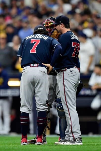 Luke Jackson of the Atlanta Braves talks with Dansby Swanson and Travis d'Arnaud of the Atlanta Braves on the mound in the seventh inning during game...