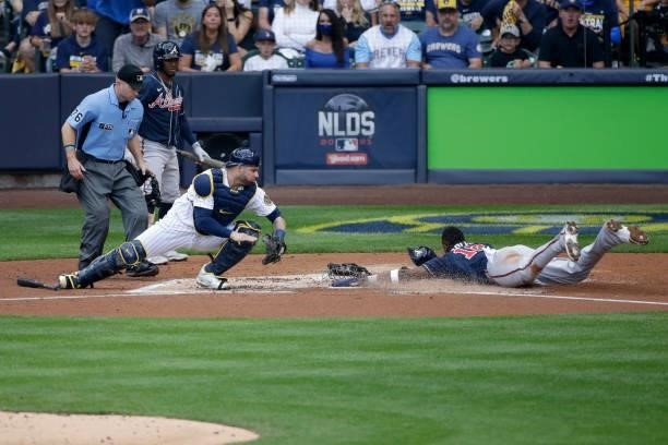 Jorge Soler of the Atlanta Braves is safe at home after avoiding a tag by Manny Pina of the Milwaukee Brewers in the third inning during game 2 of...