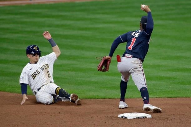 Luis Urias of the Milwaukee Brewers slides into second while Ozzie Albies of the Atlanta Braves throws to first for the double play in the ninth...