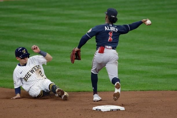 Ozzie Albies of the Atlanta Braves turns a double play to end the game as Luis Urias of the Milwaukee Brewers slides into second base during game 2...