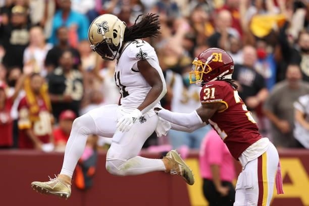 Alvin Kamara of the New Orleans Saints scores a touchdown as Kamren Curl of the Washington Football Team defends during the first half at FedExField...