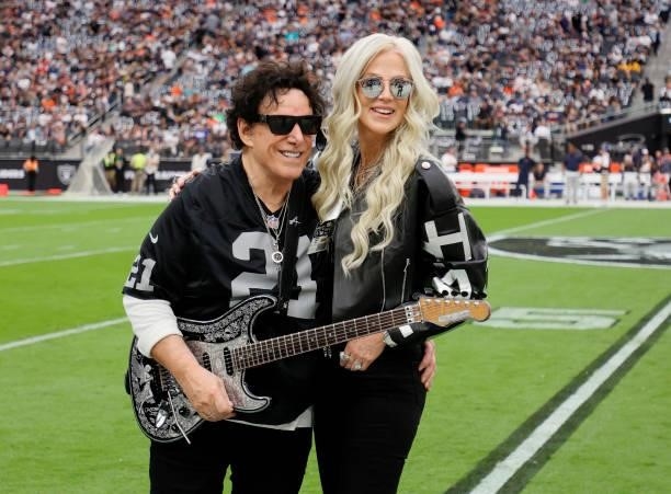 Recording artist Neal Schon of the band Journey and his wife, television personality Michaele Schon, pose on the field before Neal Schon performs the...