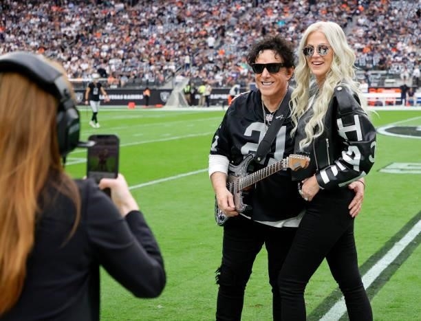 Recording artist Neal Schon of the band Journey and his wife, television personality Michaele Schon, are photographed as they pose on the field...