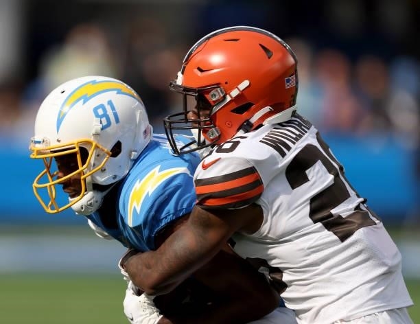 Mike Williams of the Los Angeles Chargers is wrapped up by Greedy Williams of the Cleveland Browns during a 47-42 win over the Cleveland Browns at...