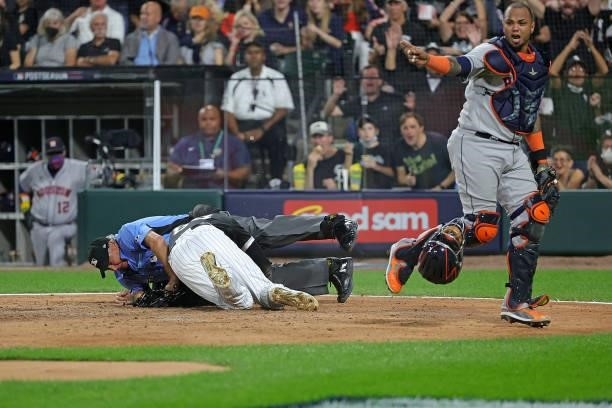 Luis Robert of the Chicago White Sox collides with umpire Tom Hallion at home plate during game three of the American League Division Series against...