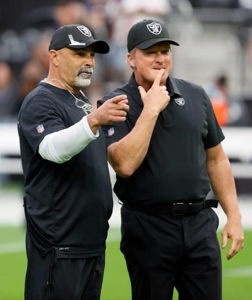 Assistant head coach/special teams coordinator Rich Bisaccia and head coach Jon Gruden of the Las Vegas Raiders talk on the field before their game...