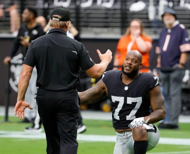 Head coach Jon Gruden of the Las Vegas Raiders greets defensive tackle Quinton Jefferson as he stretches before a game against the Chicago Bears at...