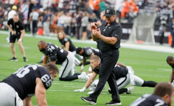 Head coach Jon Gruden of the Las Vegas Raiders talks to his players as they stretch before a game against the Chicago Bears at Allegiant Stadium on...