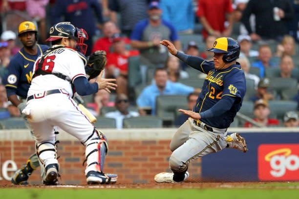 Avisail Garcia of the Milwaukee Brewers slides in to score ahead of Travis d'Arnaud of the Atlanta Braves during the fourth inning in game four of...