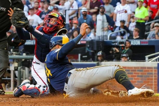 Avisail Garcia of the Milwaukee Brewers slides in to score ahead of Travis d'Arnaud of the Atlanta Braves during the fourth inning in game four of...