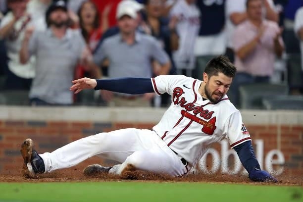 Travis d'Arnaud of the Atlanta Braves slides into score during the fourth inning against the Milwaukee Brewers in game four of the National League...