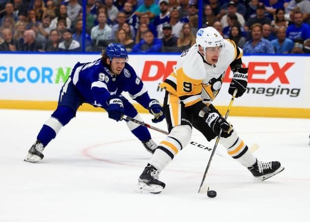Evan Rodrigues of the Pittsburgh Penguins and Mikhail Sergachev of the Tampa Bay Lightning fights for the puck during the first period of a game at...