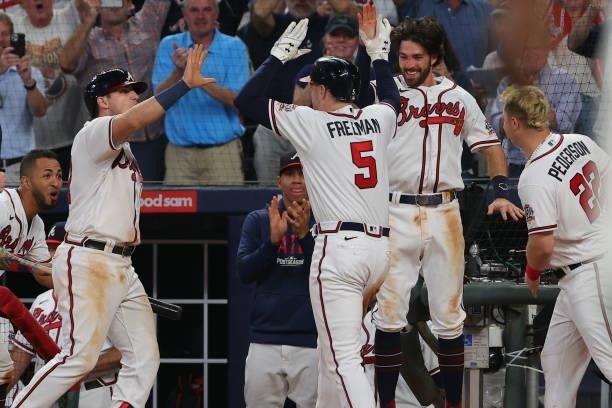 Freddie Freeman of the Atlanta Braves high fives Austin Riley and Dansby Swanson after hitting a home run during the eighth inning against the...