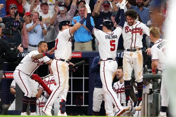 Freddie Freeman of the Atlanta Braves high fives Austin Riley and Dansby Swanson after hitting a home run during the eighth inning against the...