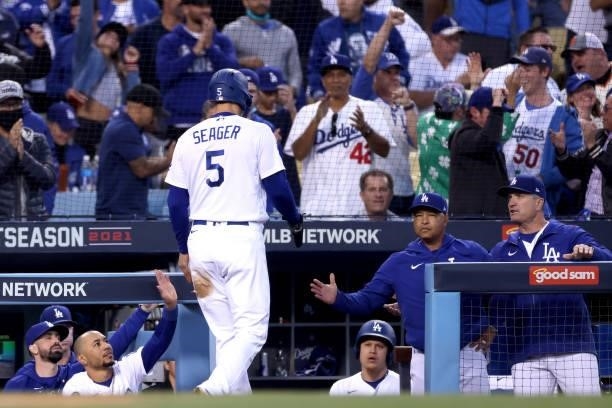 Corey Seager high fives Mookie Betts and manager Dave Roberts of the Los Angeles Dodgers after Seager scored a run on a double by Trea Turner against...