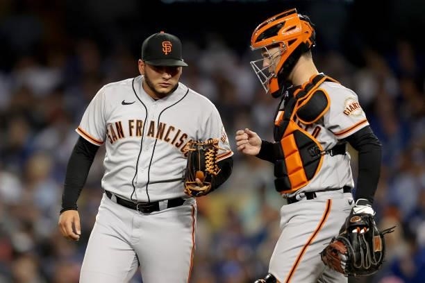 Kervin Castro talks with Buster Posey of the San Francisco Giants against the Los Angeles Dodgers during the third inning in game 4 of the National...
