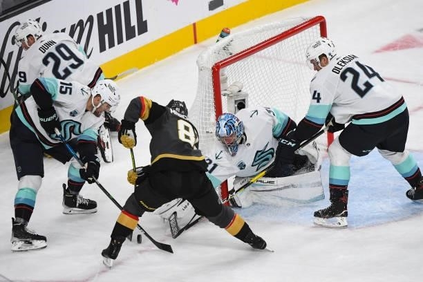 Riley Sheahan, Philipp Grubauer, and Jamie Oleksiak of the Seattle Kraken work to keep a shot by Jonathan Marchessault of the Vegas Golden Knights...