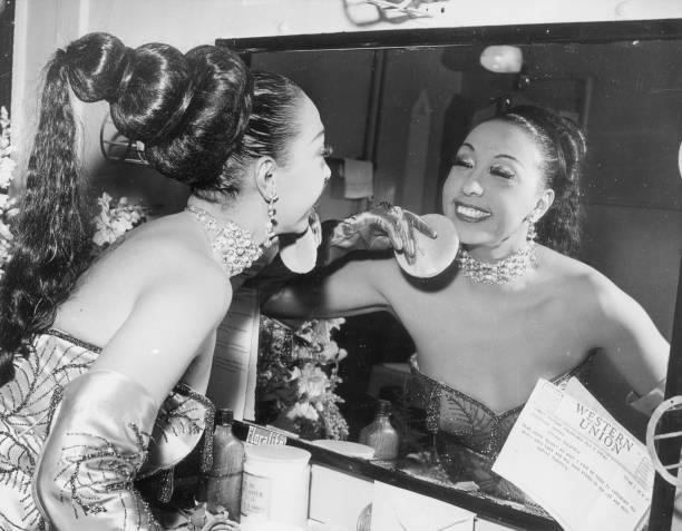 American-born cabaret singer Josephine Baker applies makeup with a powder puff in her dressing room before a performance at the Strand Theatre. A...