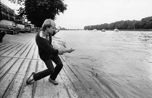Sting, lead singer and bass player with the pop group The Police, relaxes by skimming stones by the riverbank at Putney, south west London.