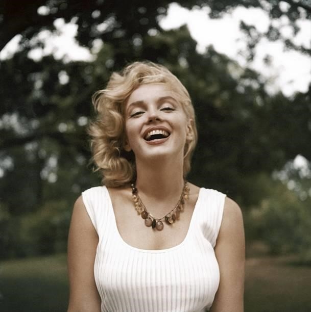 Marilyn Monroe laughs as she poses wearing an amber bead necklace in 1957 in Amagansett, New York.