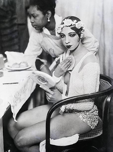 Vienna, Austria - Josephine Baker getting ready in her dressing room. She is depicted putting on makeup looking into a mirror. BPAII