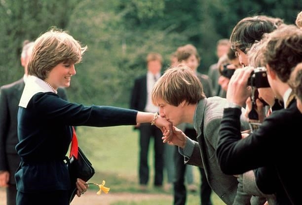 Schoolboy Nicholas Hardy kisses Lady Diana Spencer's hand after giving her a daffodil, during her visit to Cheltenham.