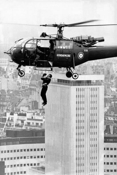Jean-Paul Belmondo suspendu à un hélicoptère lors du tournage du film 'Peur sur la ville' réalisé par Henri Verneuil en 1974 à Paris, France.